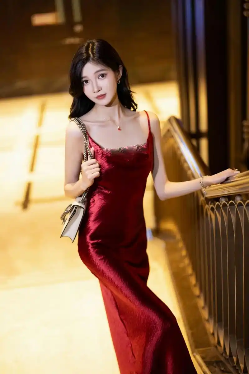 她身着酒红衣裙,脚踏细高跟鞋,身姿优雅.秀发如瀑,配饰闪耀,妆容精致.