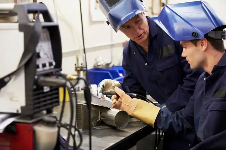 engineer teaching apprentice to use tig welding machine