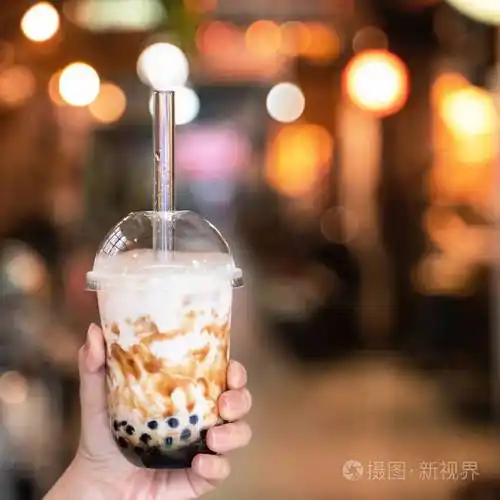 在台湾夜市年轻女孩拿着一杯红糖味的木薯珍珠泡奶茶展示特写博克