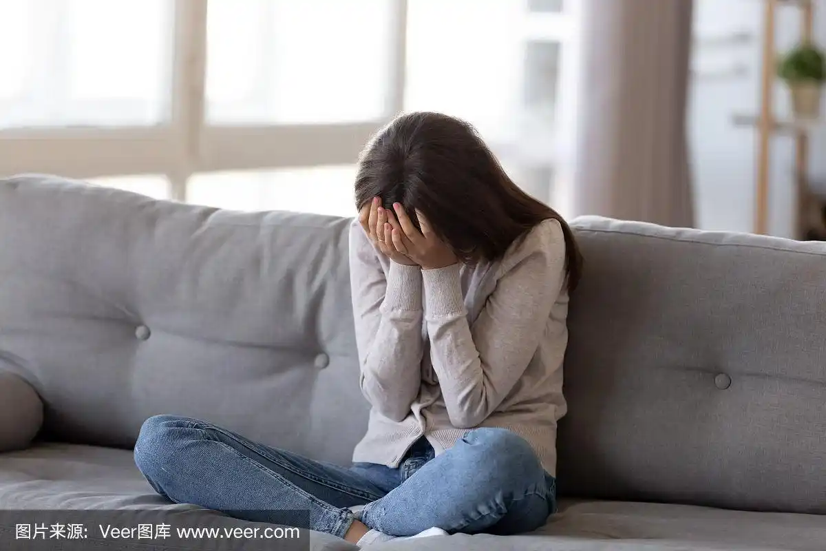 沮丧的年轻女子捂着脸,独自在家哭泣