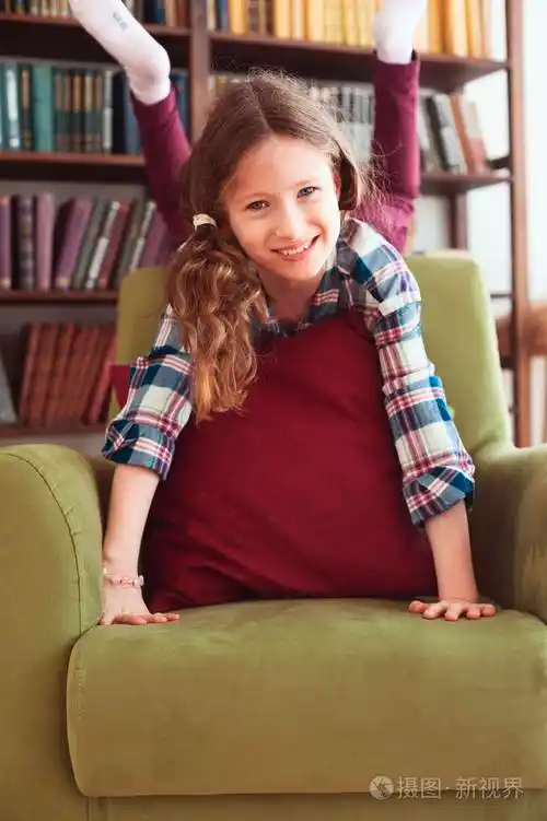淘气有趣快乐的孩子女孩在家玩背景上有书架