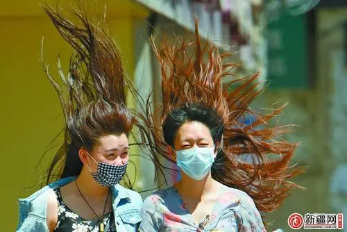 15日,光明路上两名行人的长发被大风吹起.
