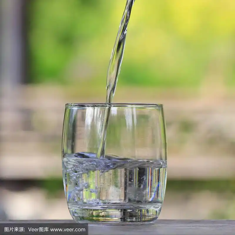 在自然的绿色背景上倒水的玻璃杯.