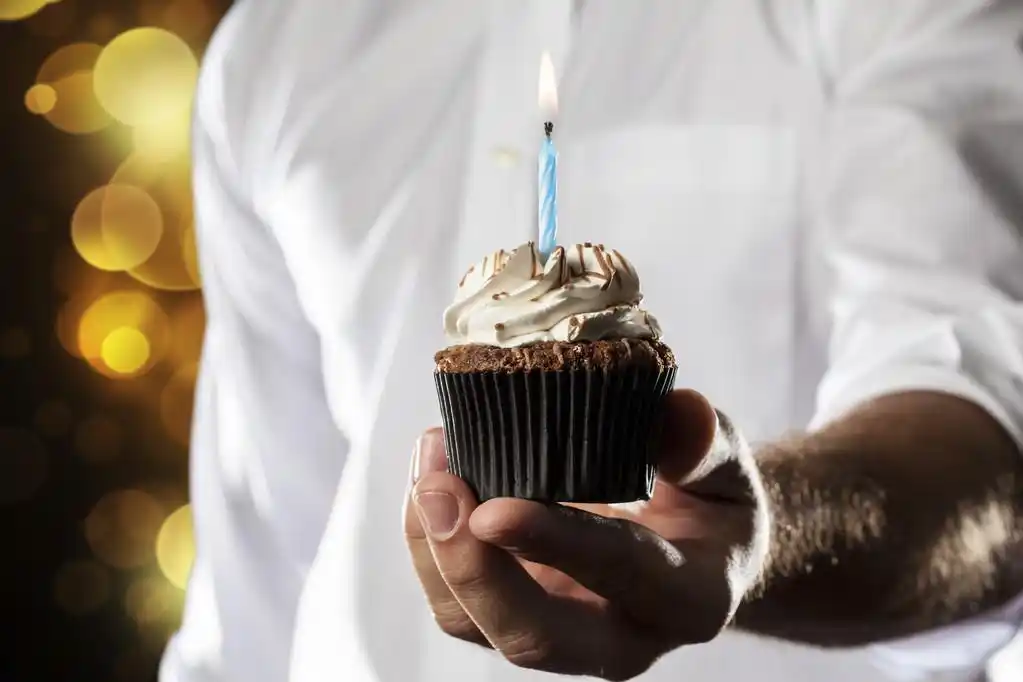 生日快乐,一个人拿着蜡烛的蛋糕给的姿态.