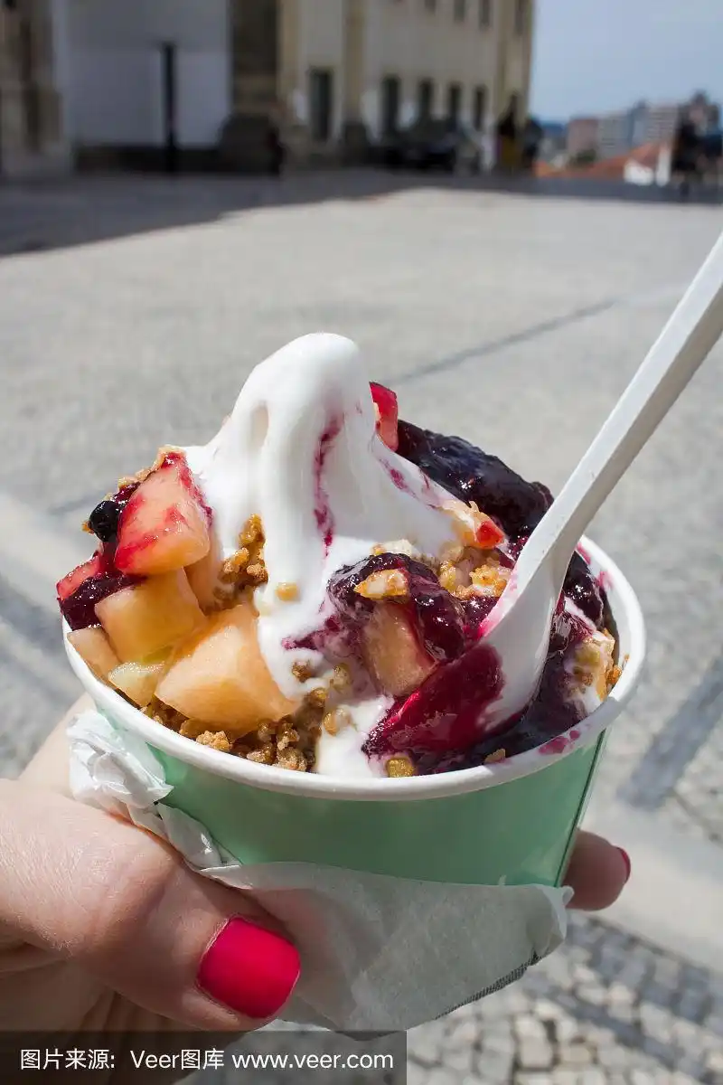 在模糊的街道背景上的女人手拿新鲜冰淇淋的特写.