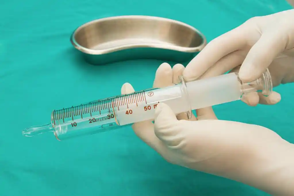 在无菌纸盒和玻璃 b 拿玻璃注射器的医生的手