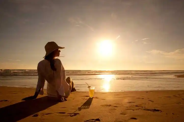 落日海边坐在地上的女人