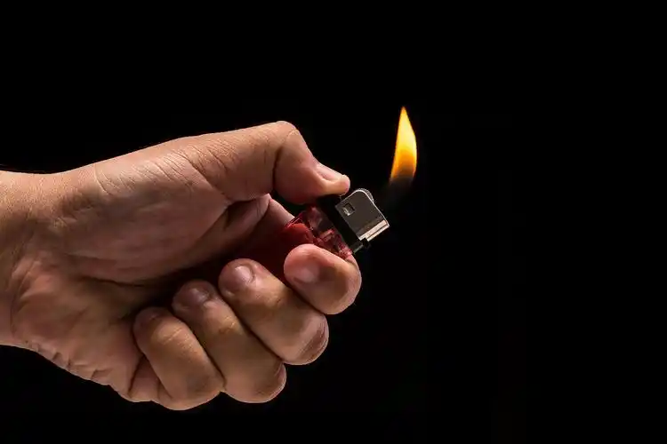 黑色背景中打开的打火机手里拿的燃烧气体打火机.工作室拍摄孤立上黑