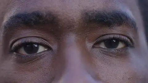 缓慢微笑面对镜头前黑人男性眼睛睁开的特写肖像