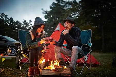 篝火前取暖休闲的野营男女图片素材