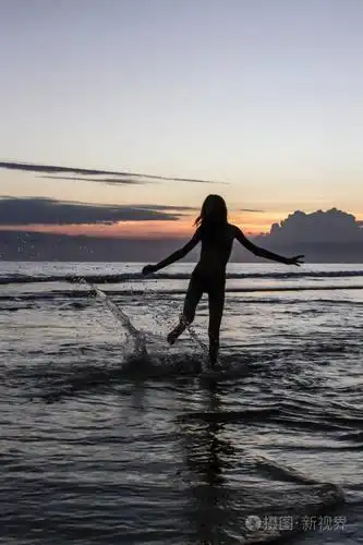 在海滩上夕阳背景下奔跑的女孩剪影