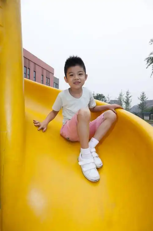 小男孩在幼儿园内玩滑梯