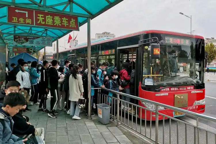 10月24日 排队登上郧十无座位公交车的学生.