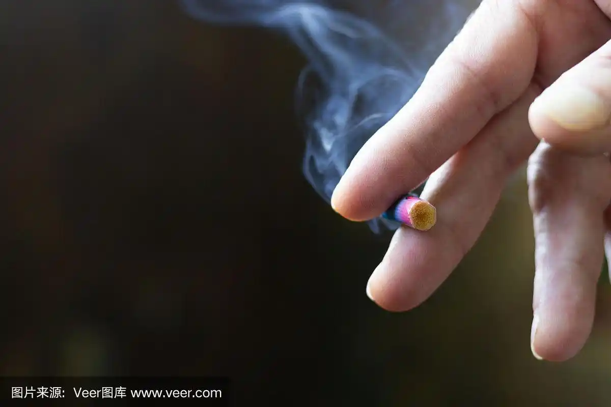 男人的手指拿着一根点燃的烟