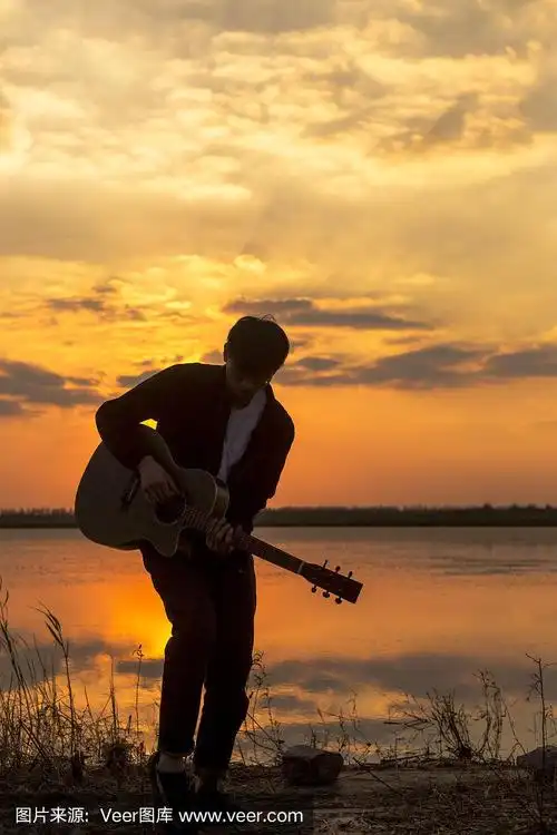 夕阳下,挎着吉他的男人的剪影