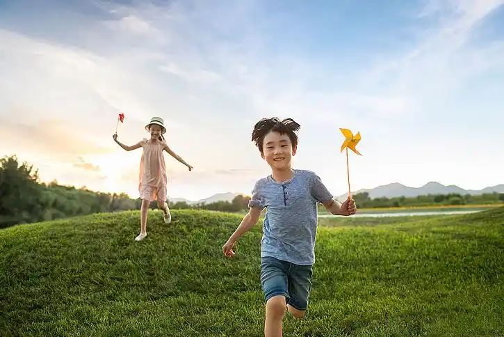 儿童拿着风车在草地上奔跑