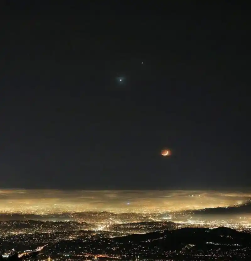 灯火辉煌的城市上空,月亮,金星和木星一起争辉!