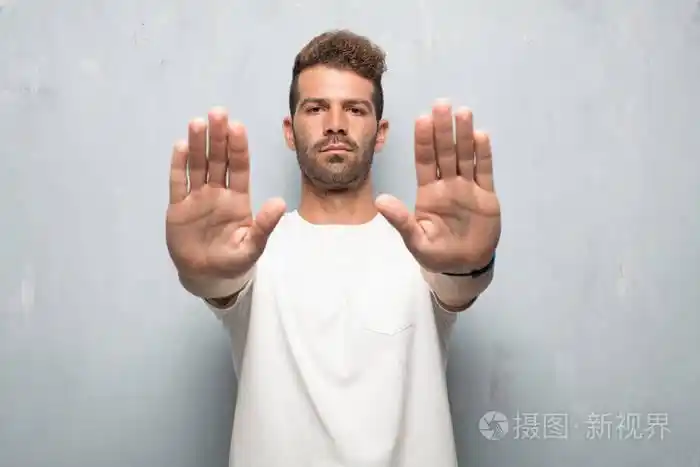 年轻的帅哥信号停止,双手掌朝前,严肃而严厉的表情令人生畏.