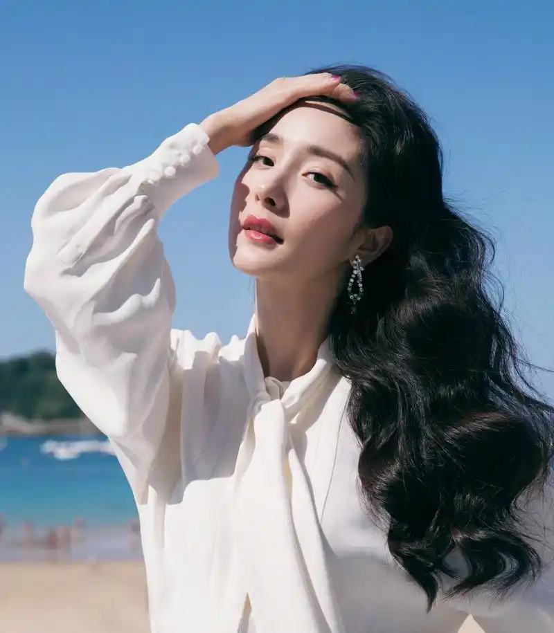 图片中的杨幂穿着一件白色宽松的衣服,看背景好像是在海滩拍摄的,显得
