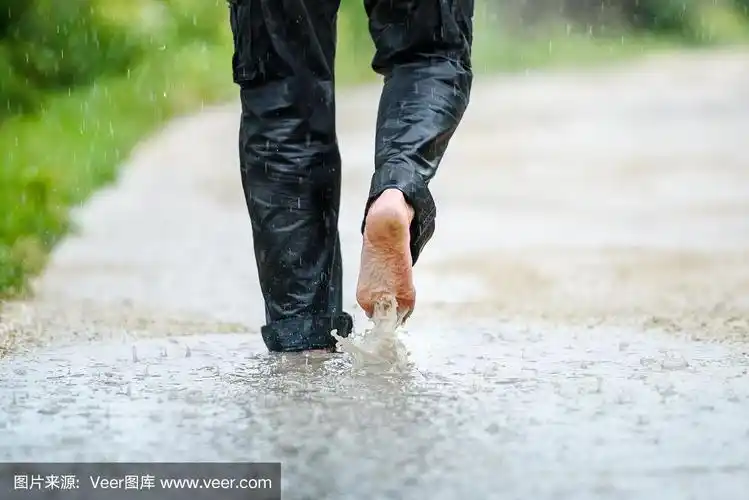 一个男人在雨中赤脚在水坑里
