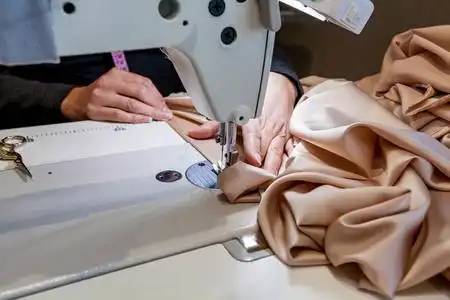 货架上的许多珍贵布料卷缝纫机和牛仔裤布料的一部分女工在缝纫车间