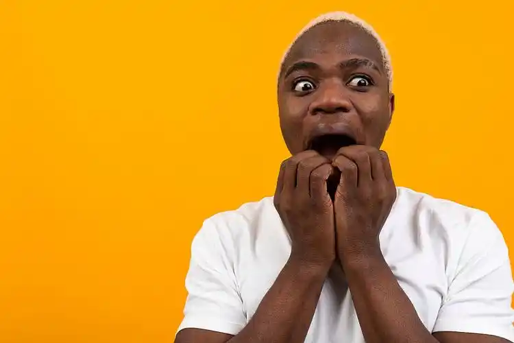 想象一下一个穿着白色t恤的非洲黑人在黄色背景下展开双臂摆出的姿势