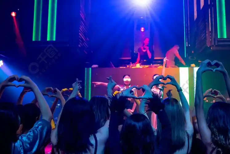一群人在迪斯科夜总会随着舞台上dj的音乐节拍跳舞新年晚会和夜生活