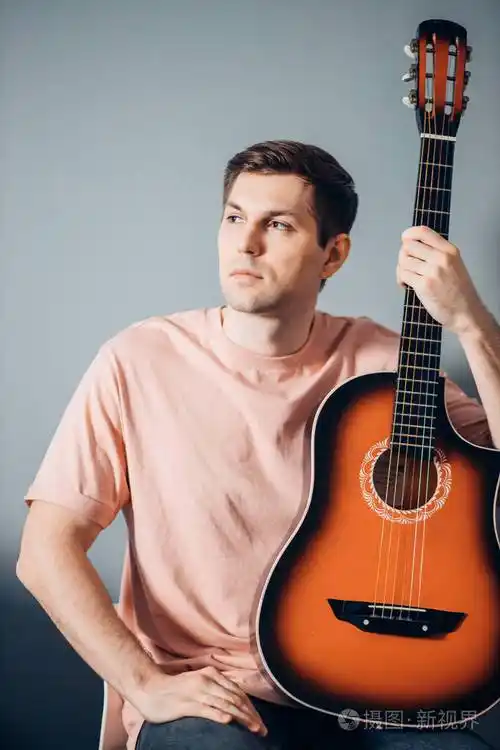 年轻漂亮的白人男子与吉他单独摆姿势的肖像