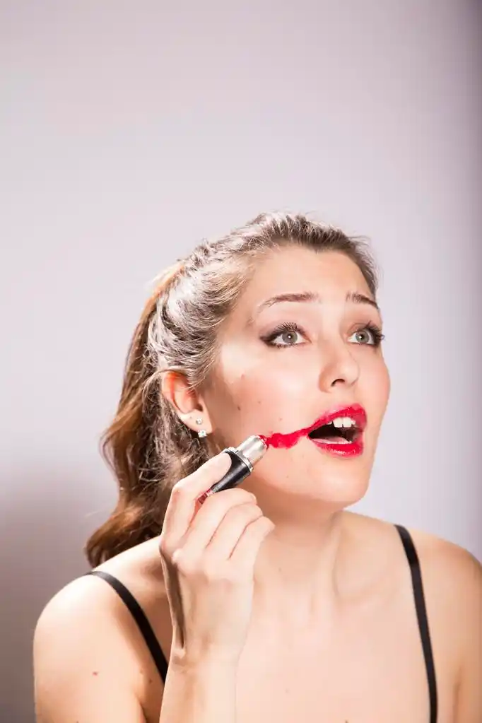 年轻女子在她的脸上涂抹口红