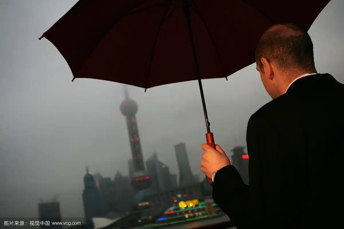 阴雨天外滩黄浦江边一位外国商务人士拿伞背影