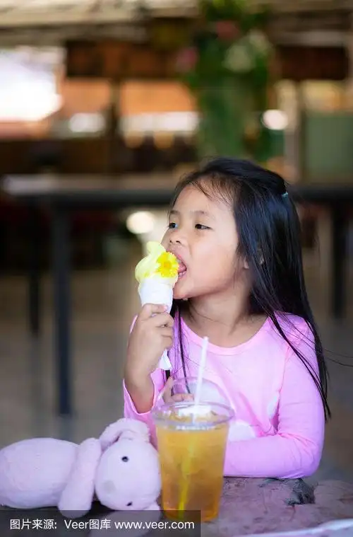 亚洲小女孩吃冰淇淋,饮料和娃娃室内