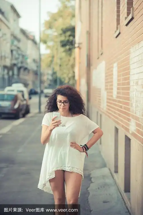 年轻美丽的摩洛哥卷毛女人使用智能手机