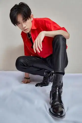 易烊千玺最新穿搭造型,身穿橘红色夹克衫搭配修身长裤和皮靴