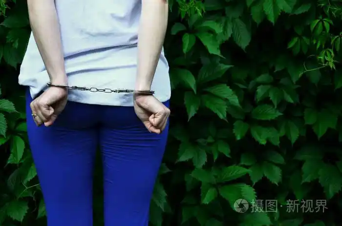 一个年轻的犯罪女孩的身体碎片与手在一个绿色的盛开的常春藤叶背景的