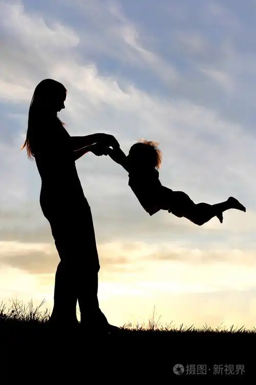 在日落时玩外面的孩子的母亲的剪影
