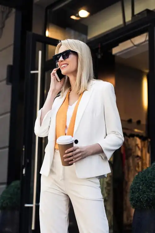 微笑时尚年轻女子在街上用智能手机交谈