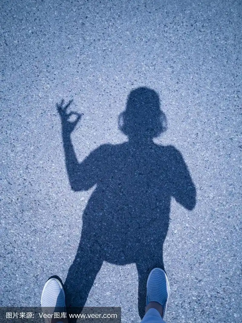 柏油路上一个女孩的影子.阳光下的阴影.